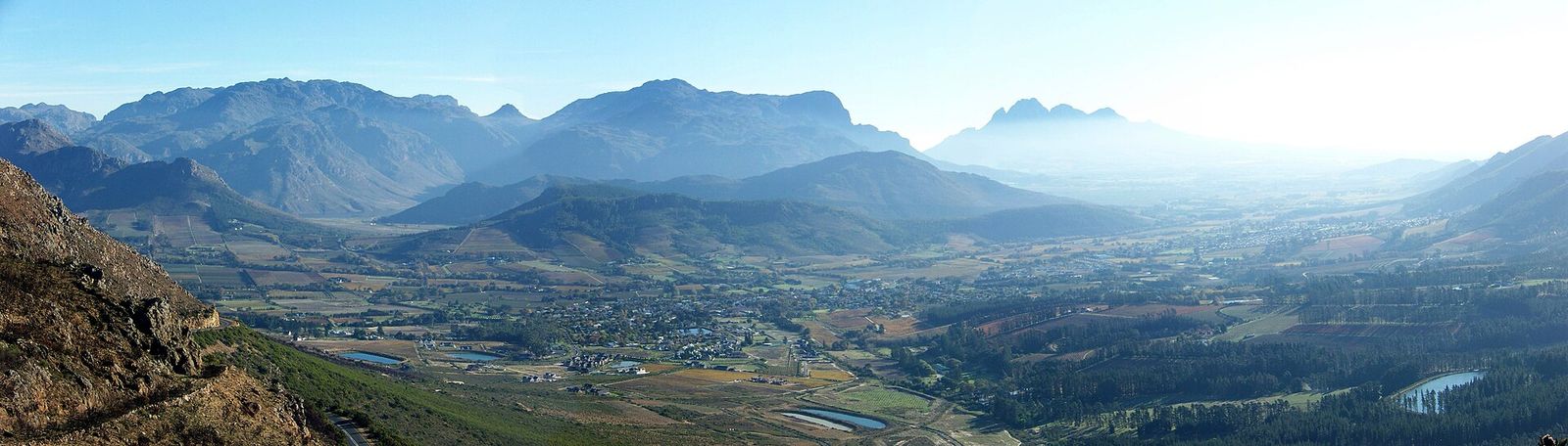 A South African town nestled against dramatic mountains, seen in warm morning light