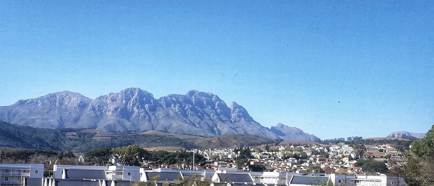 Historic Cape Dutch architecture and oak-lined streets in Stellenbosch, vineyards and mountains beyond